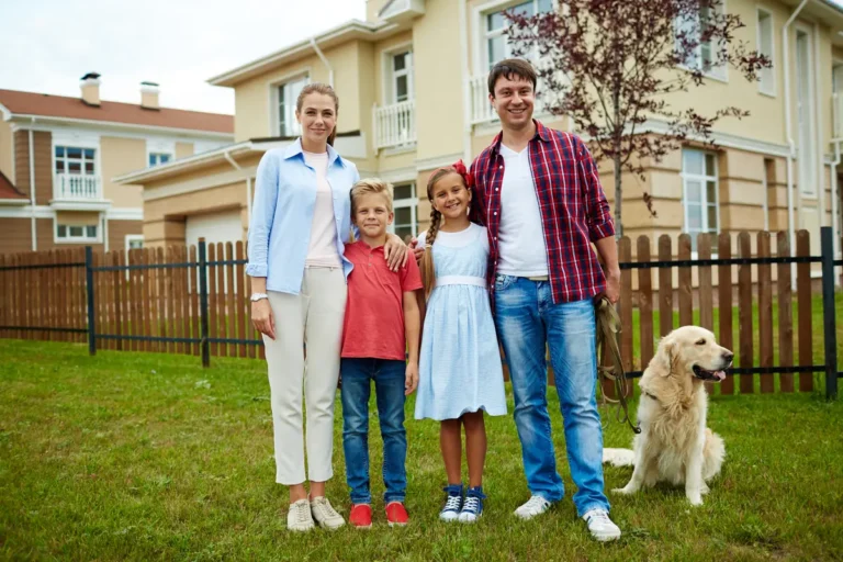 Parents, deux enfants et leur chien posant devant leur maison
