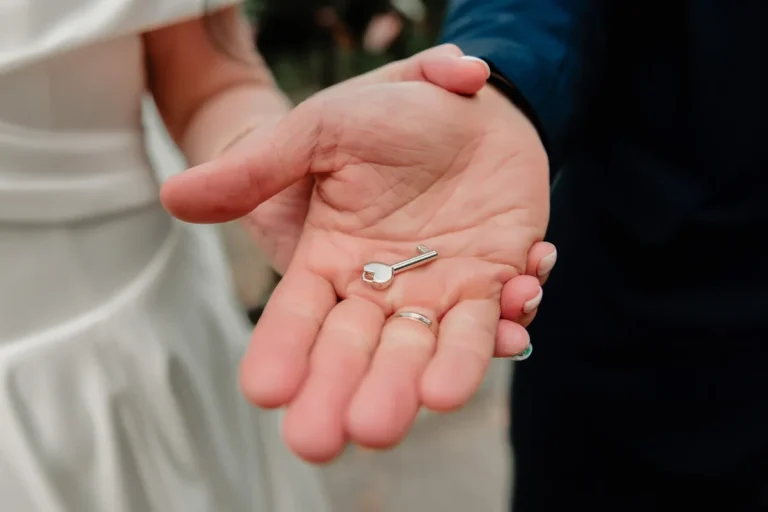 Main tenant une clé, alliance au doigt, symbole des biens acquis pendant le mariage