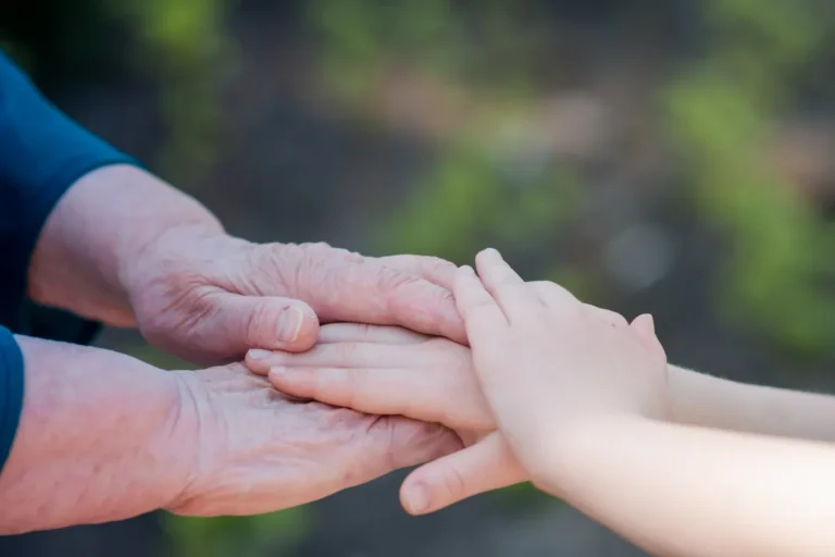 Main d'adulte et main d'enfant réunies dans un jardin, symbole de la transmission