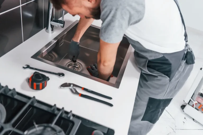 Homme réparant l'évier de la cuisine avec ses outils