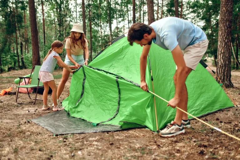 Famille montant une tente en forêt pour des vacances à petit prix
