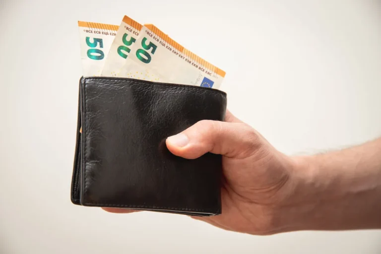Main tenant un portefeuille rempli de billets de 50 euros