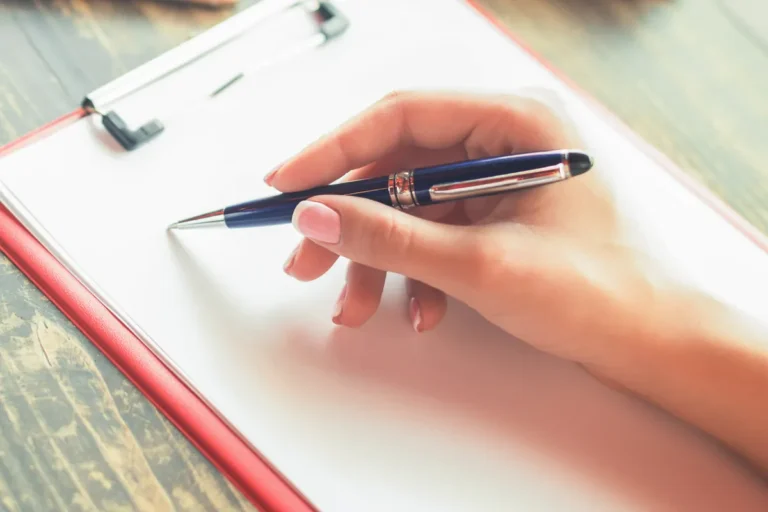 Main tenant un stylo au-dessus d'un bloc-notes, vérifications avant de signer un crédit