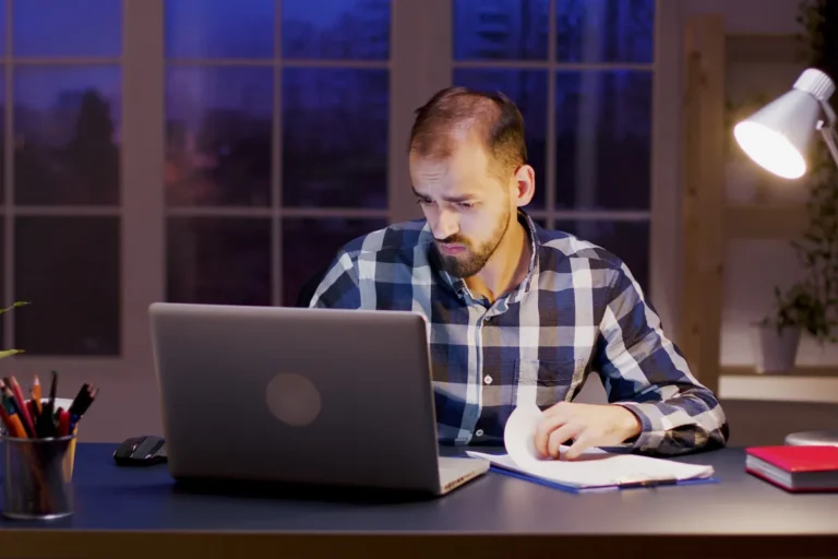 Homme travaillant tard à son bureau à domicile pour un revenu complémentaire