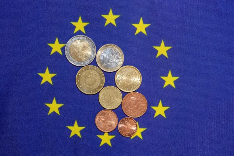 Pièces en euros de toutes valeurs posées au centre d'un drapeau européen étoilé