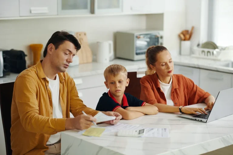 Parents et enfant remplissant des papiers à la table de la cuisine