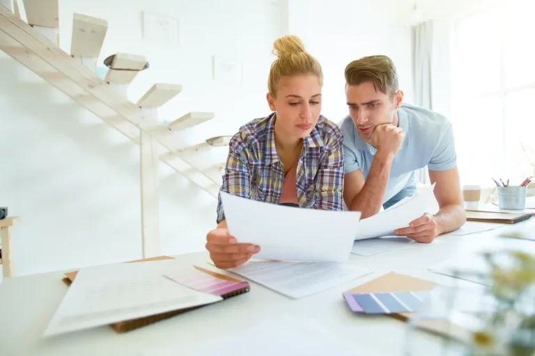 Jeune couple étudiant des documents à la maison pour un projet immobilier
