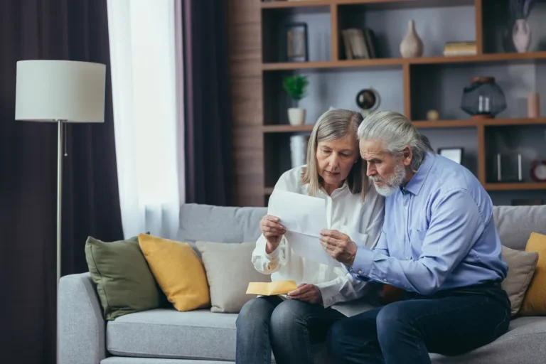 Couple de seniors lisant attentivement un courrier sur leur canapé