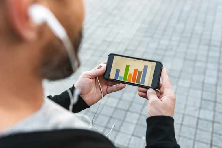 Homme consultant un graphique en barres sur son smartphone, suivi de budget sur application