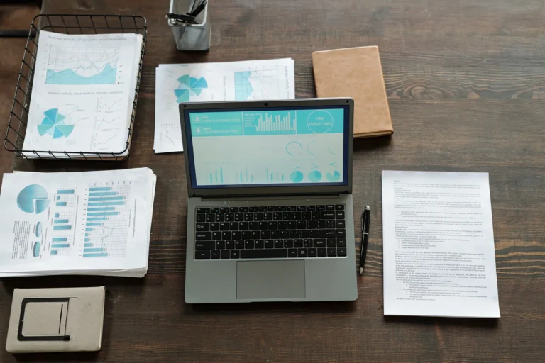 Bureau en bois vu du dessus avec un ordinateur portable, des rapports imprimés avec graphiques et des notes